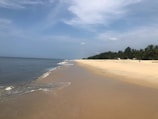 a sandy beach next to the ocean under a blue sky