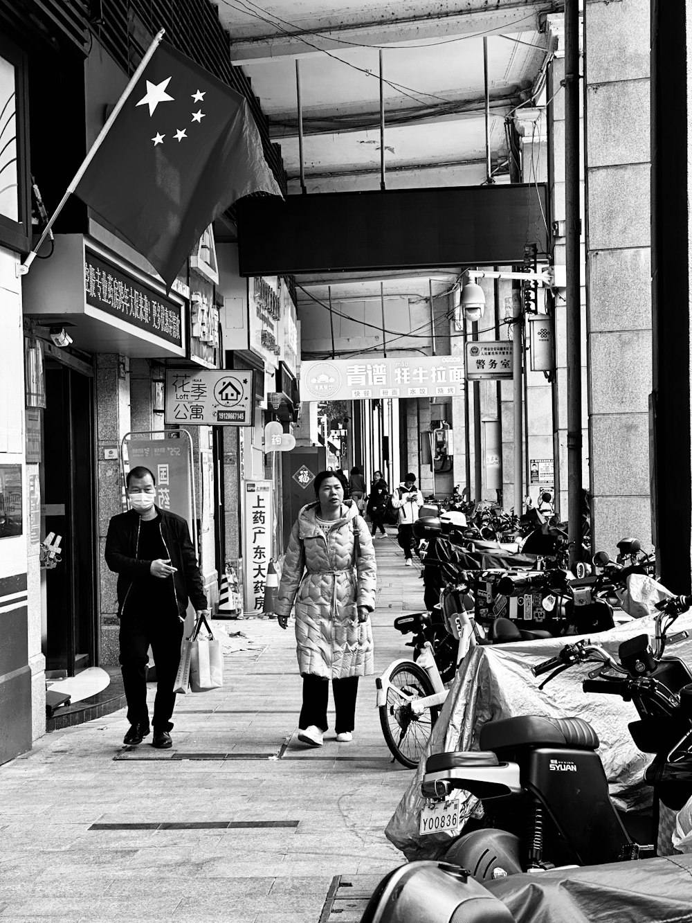 a couple of people walking down a street next to motorcycles