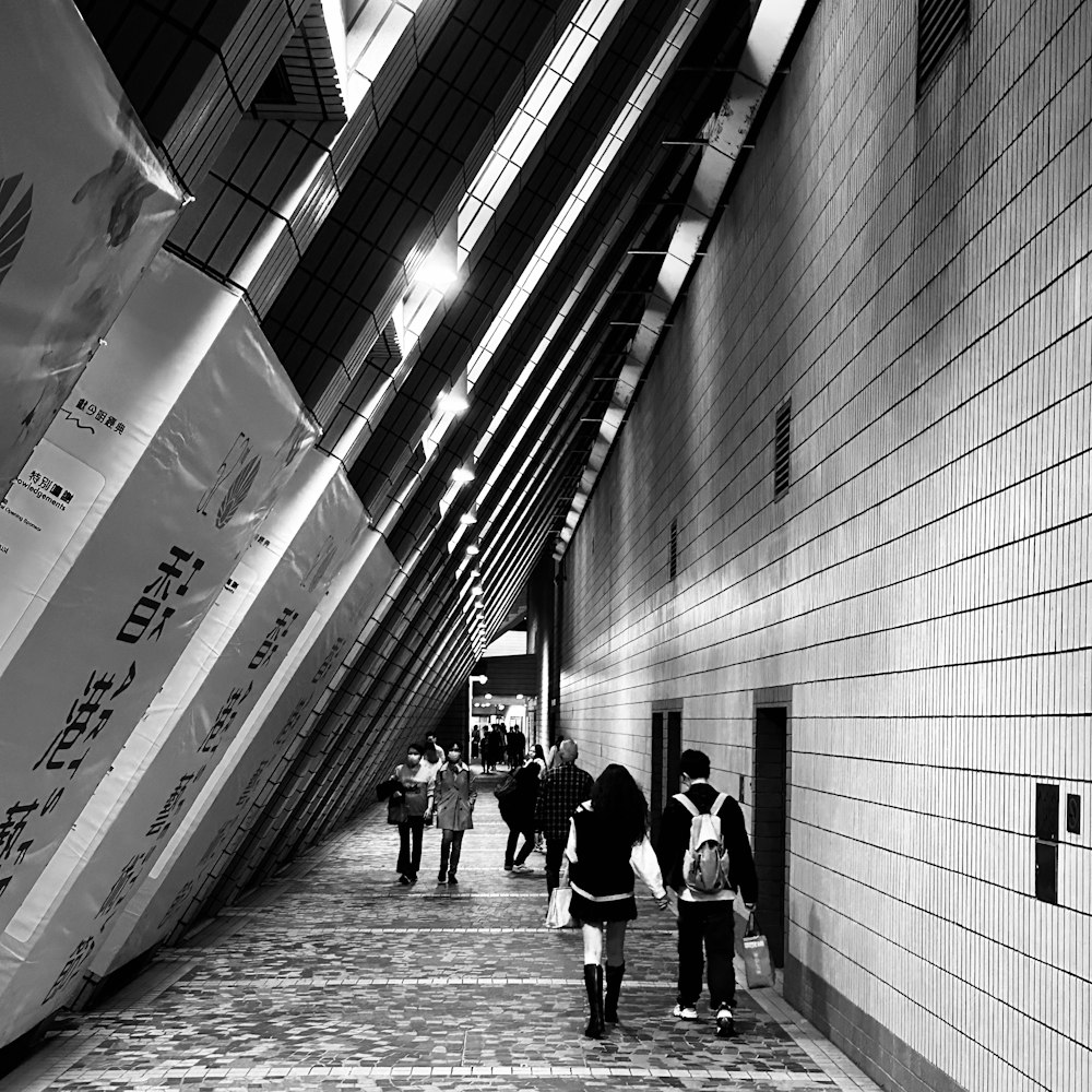 a black and white photo of people walking down a hallway