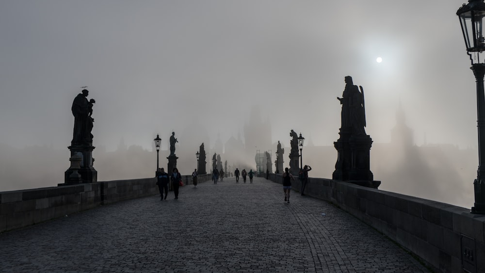 a group of people walking across a bridge on a foggy day