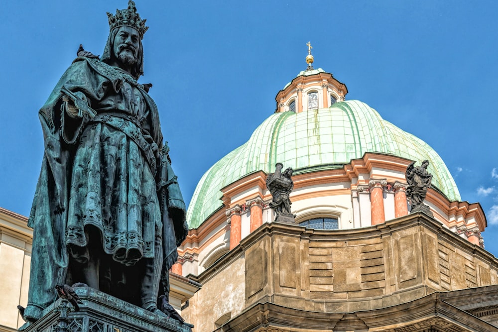 a statue stands in front of a domed building