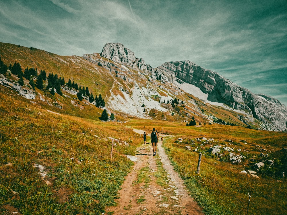 a person walking down a dirt road in the mountains