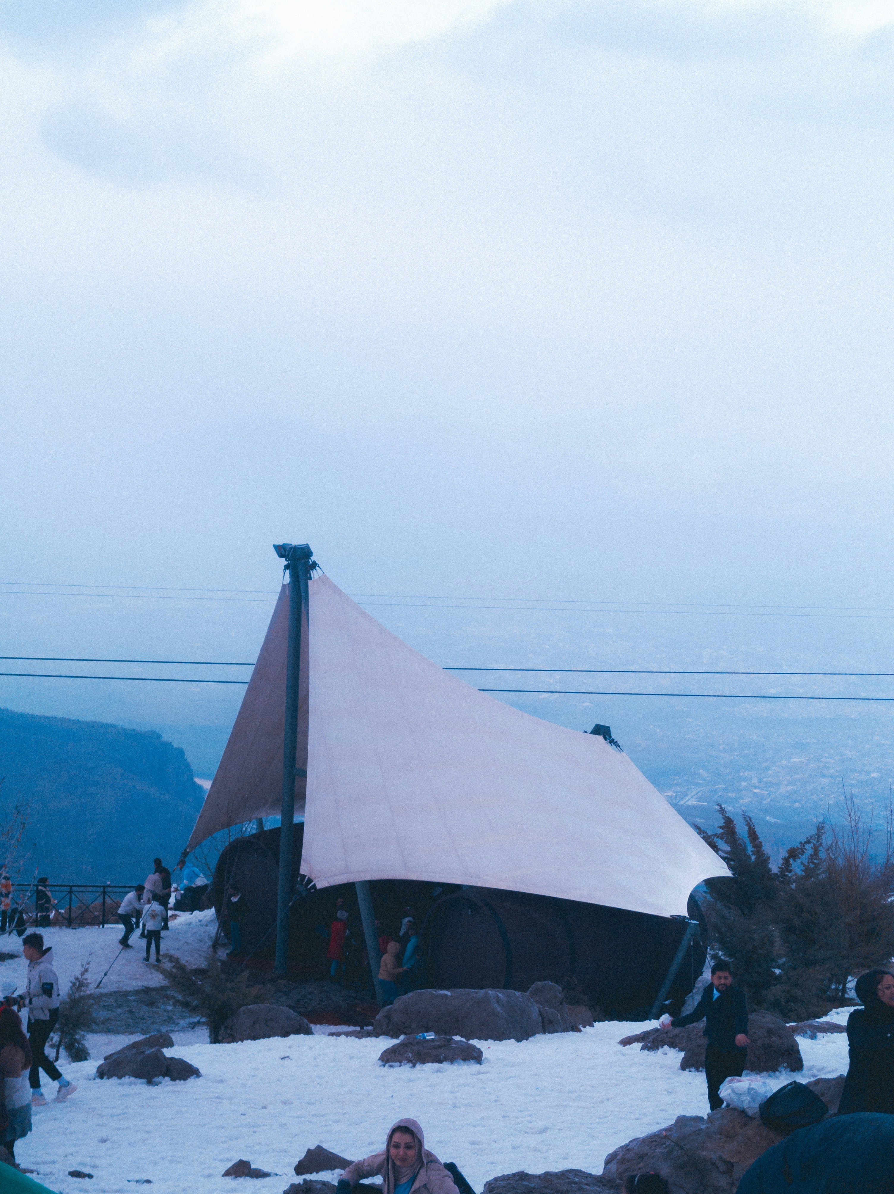 a group of people standing around a tent in the snow