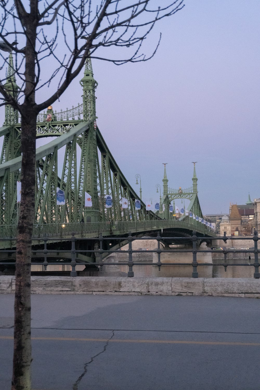 a large green bridge over a river next to a tall building