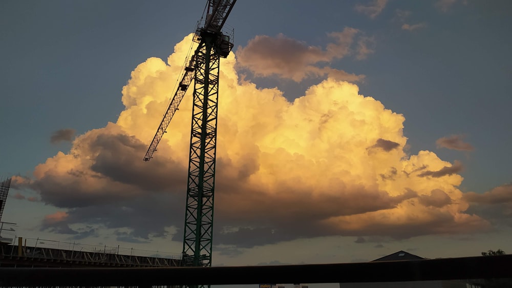 a crane is silhouetted against a cloudy sky