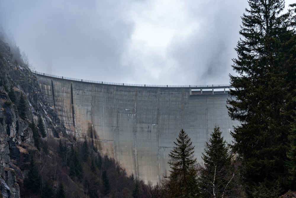 a large dam surrounded by trees on a cloudy day