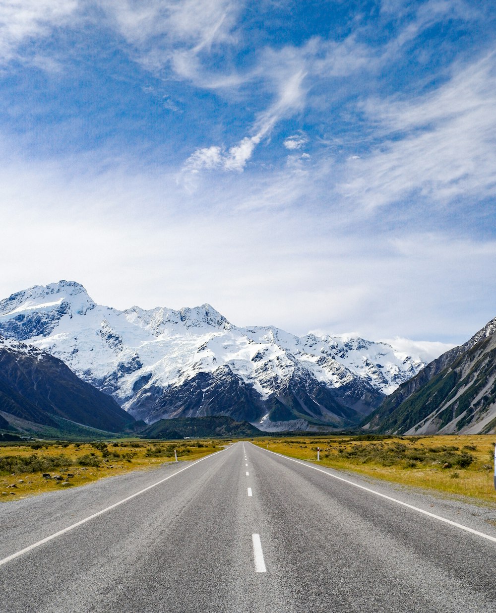 an empty road with mountains in the background