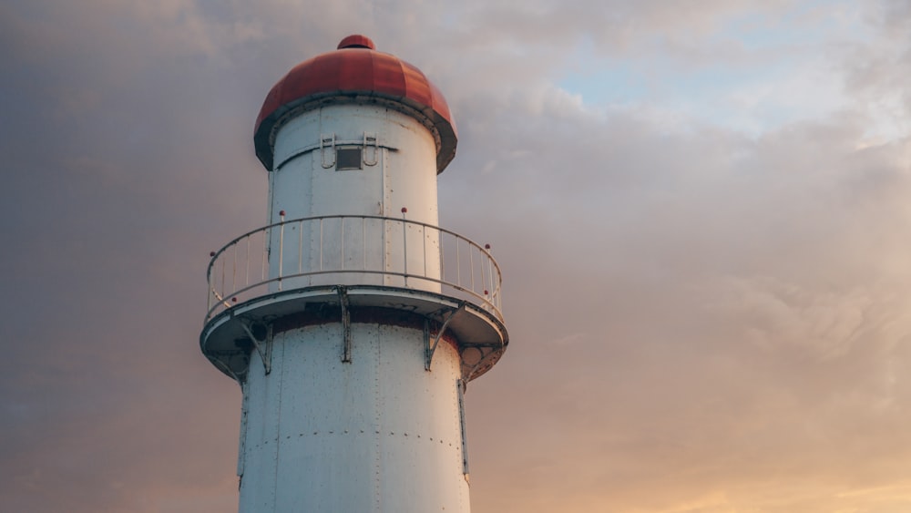 a white and red lighthouse under a cloudy sky