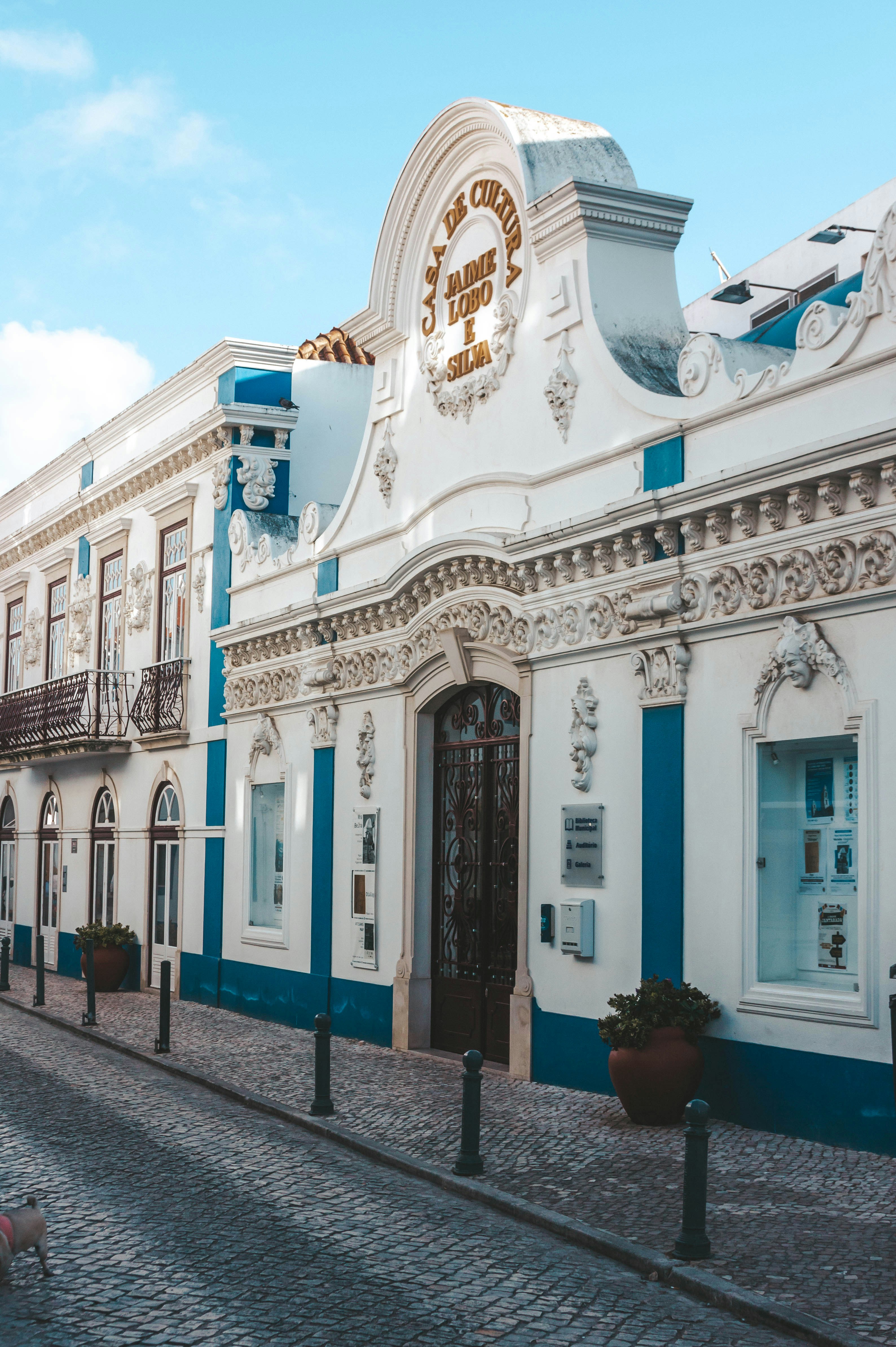 un edificio bianco con finiture blu su una strada di ciottoli