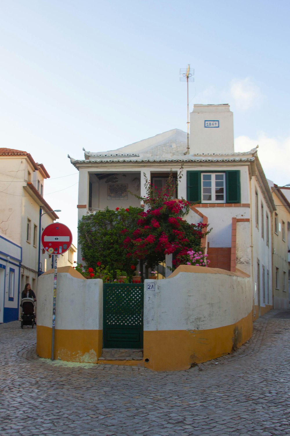 Une maison blanche avec des volets verts et un panneau d’arrêt rouge