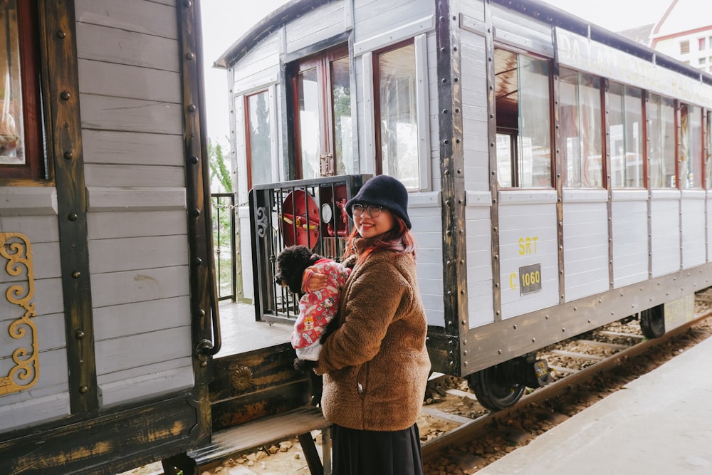 a woman holding a child standing in front of a train