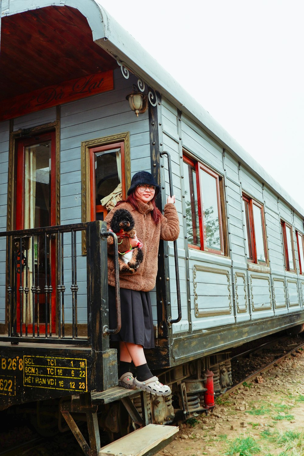 a woman holding a dog standing on a train car