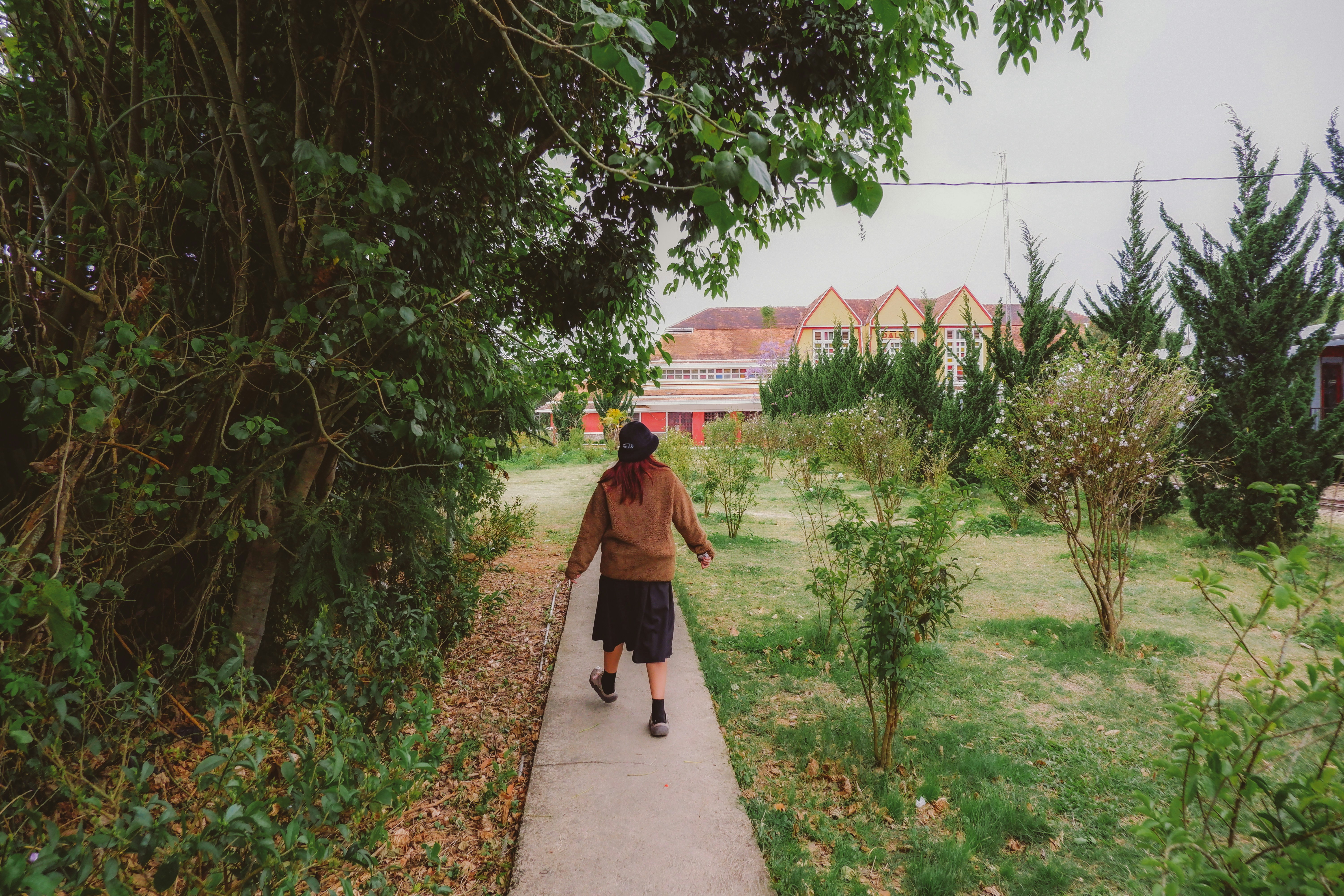 a man walking down a sidewalk next to a lush green field
