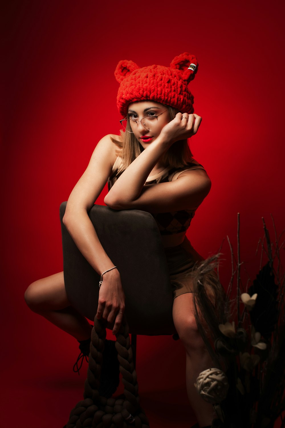 a woman wearing a red knitted hat sitting on a chair