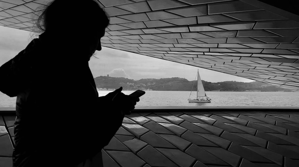 a woman looking at her cell phone while standing next to a body of water