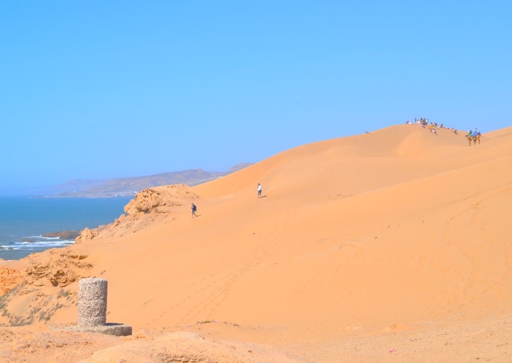 a group of people riding horses on top of a sandy hill