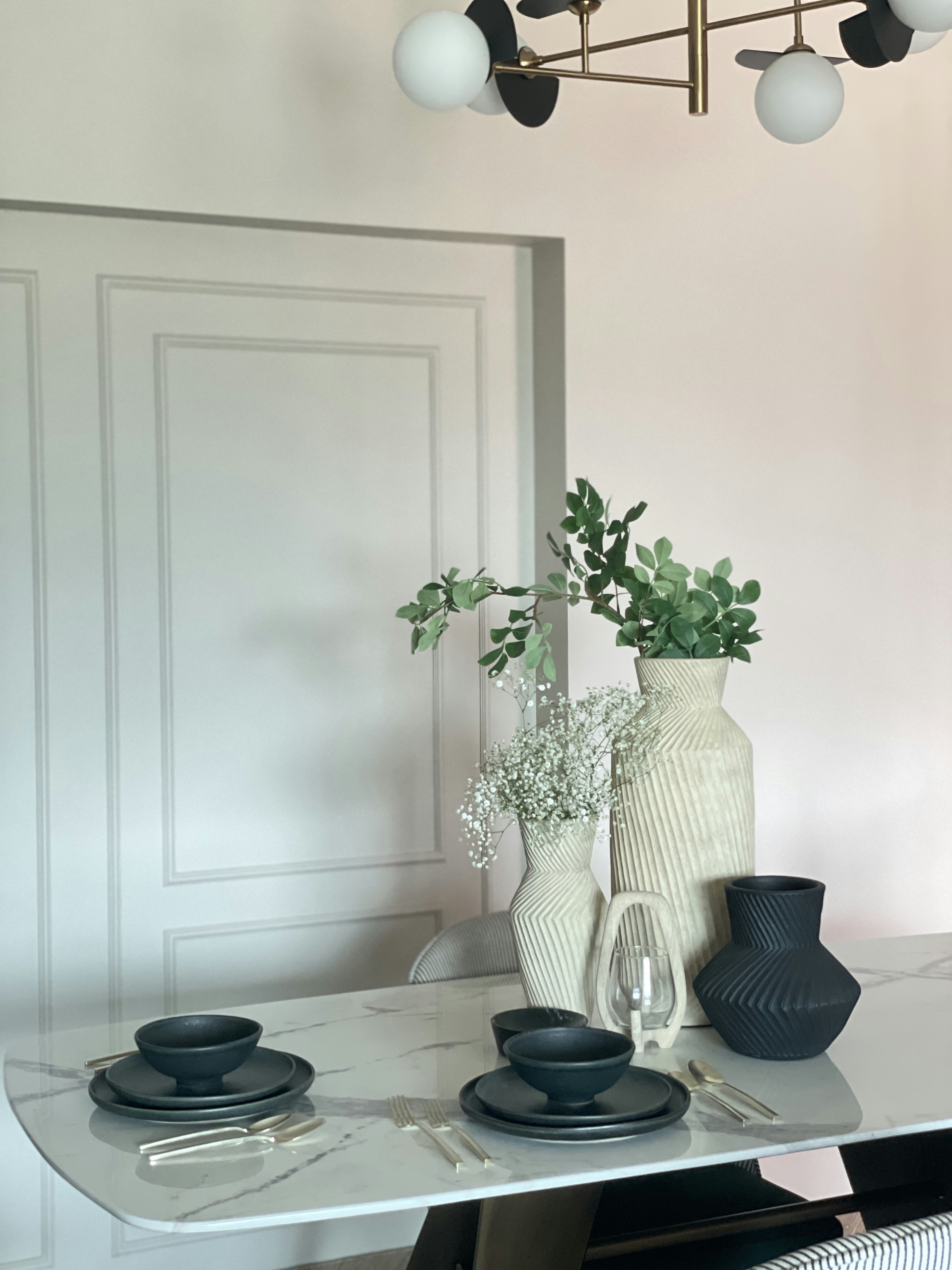 a dining room table with plates and vases on it