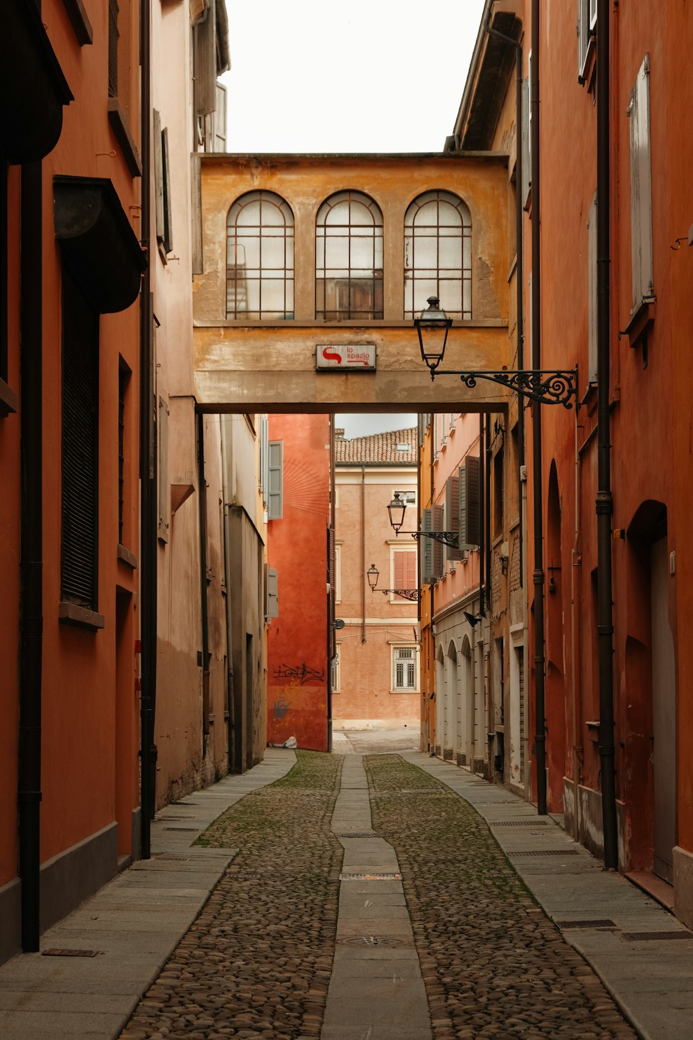 a narrow alley way with a clock on the wall