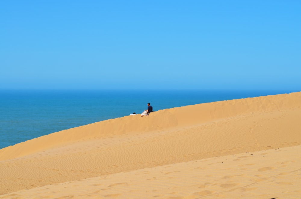 una persona seduta in cima a una duna di sabbia