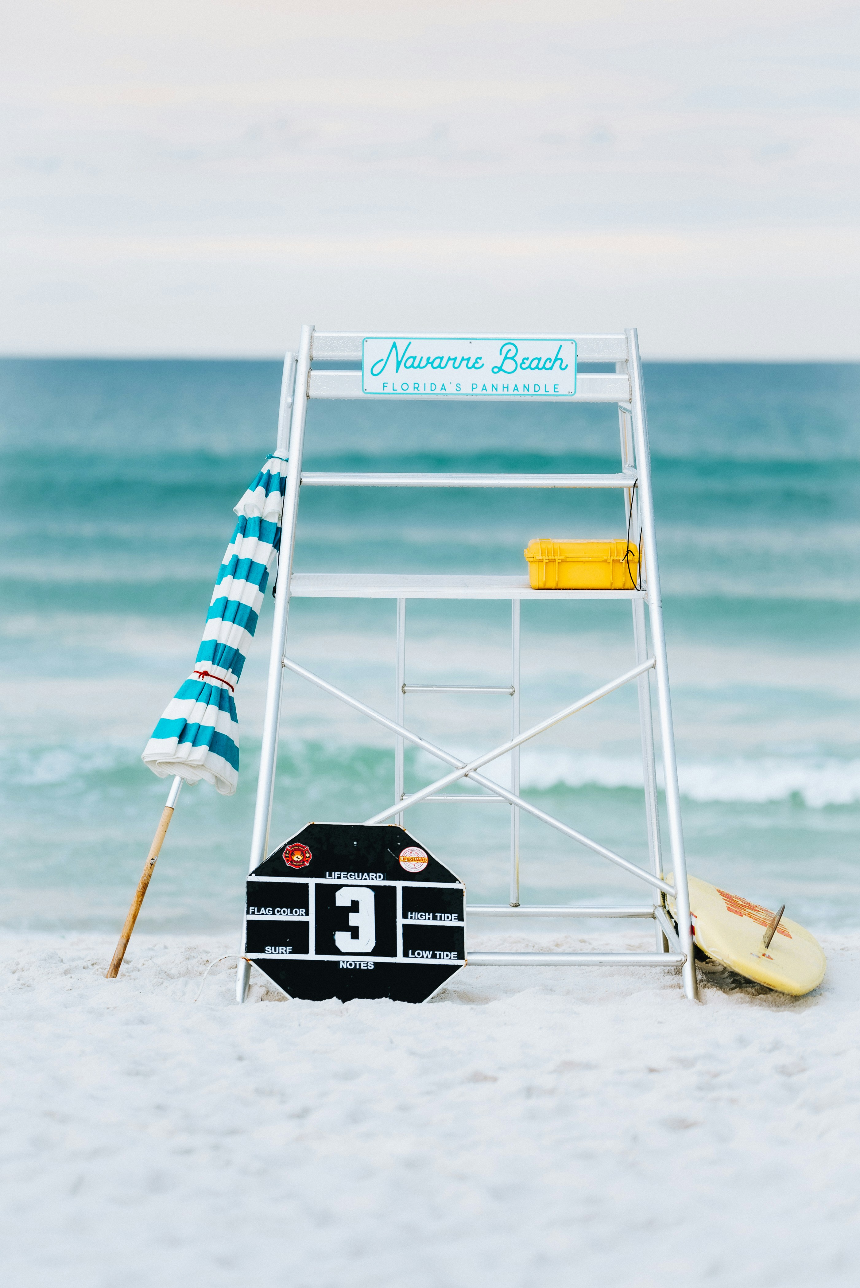 a lifeguard stand on the beach with a surfboard