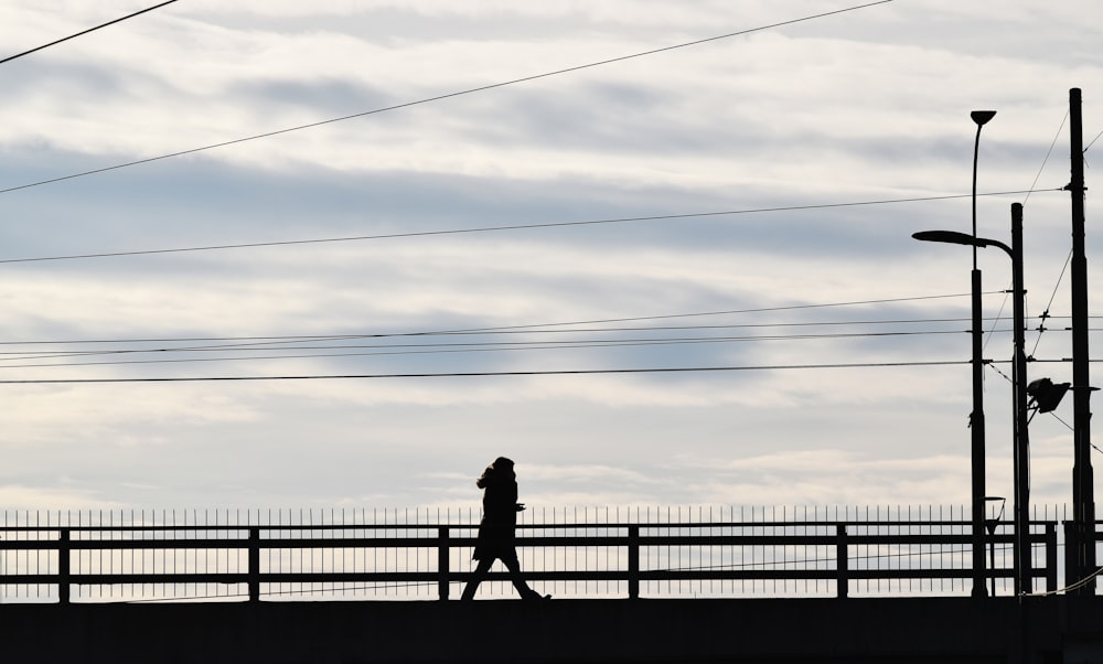 a person walking across a bridge with power lines in the background