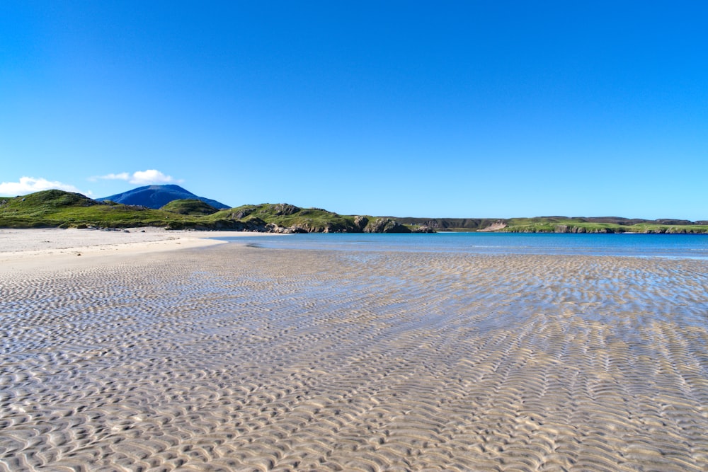 una spiaggia sabbiosa con una montagna sullo sfondo