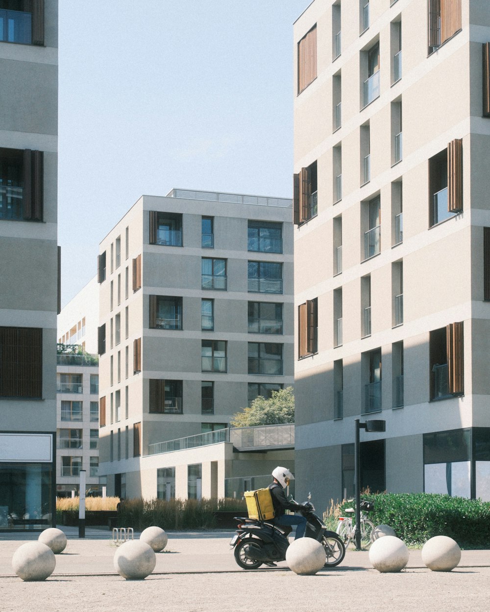 a man riding a motorcycle down a street next to tall buildings