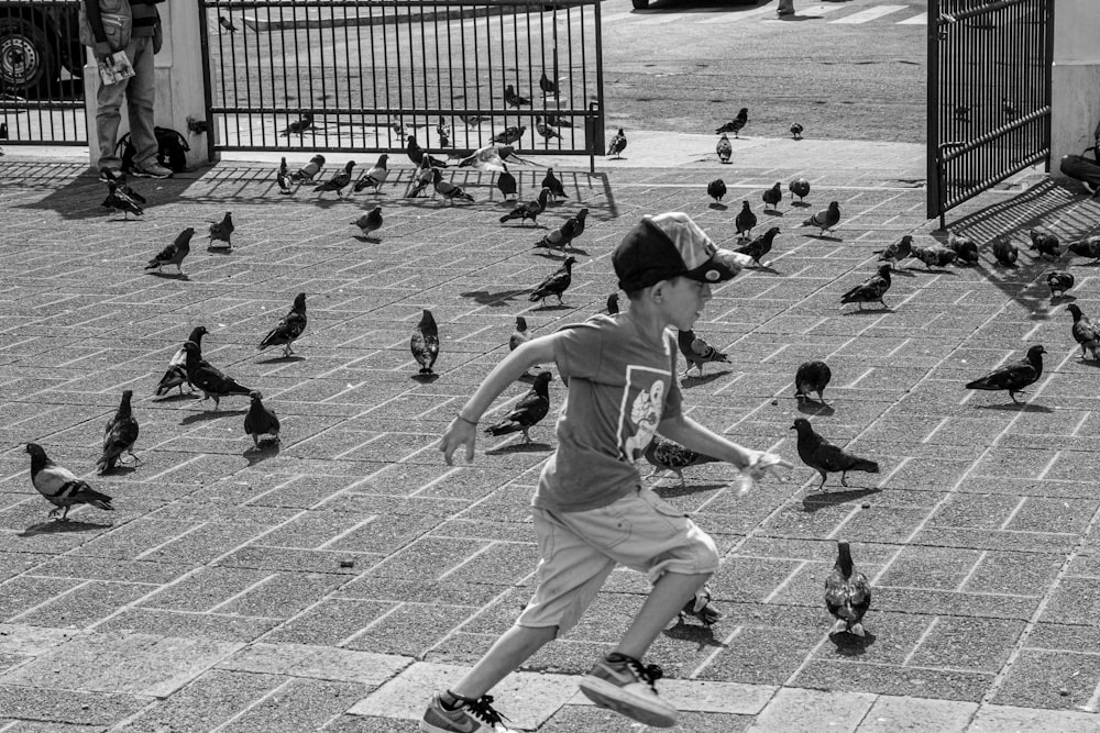 a young boy running through a flock of pigeons