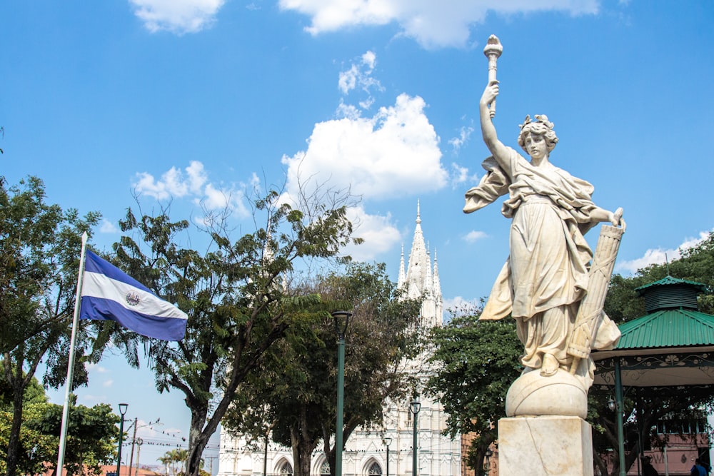 a statue of a woman holding a cup in front of a building