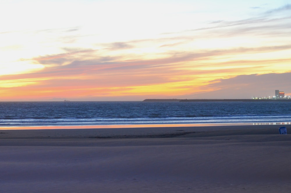 a person walking on a beach at sunset