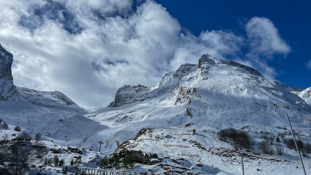 a mountain covered in snow under a cloudy blue sky