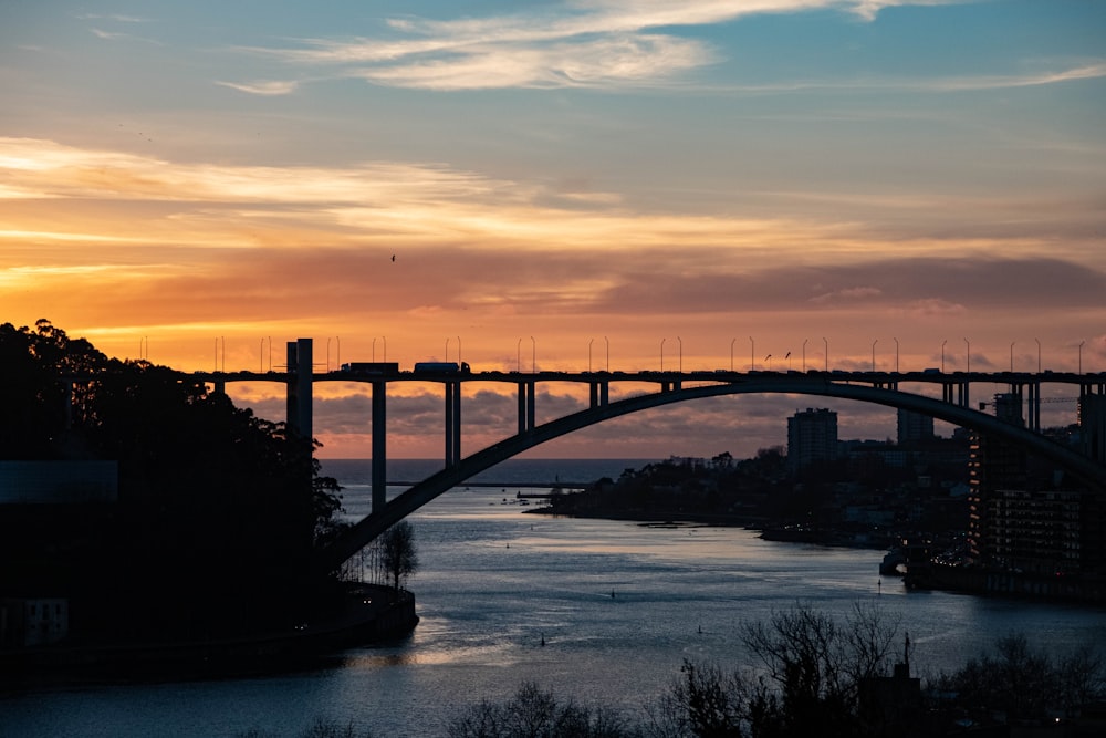 a bridge over a river with a sunset in the background