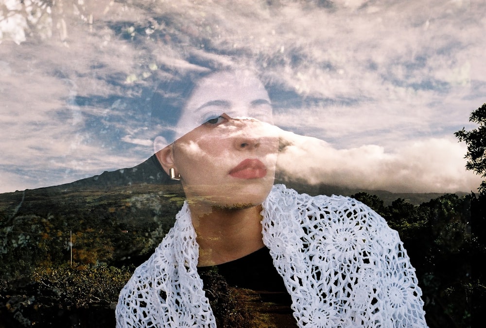 a woman looking through a window with a mountain in the background