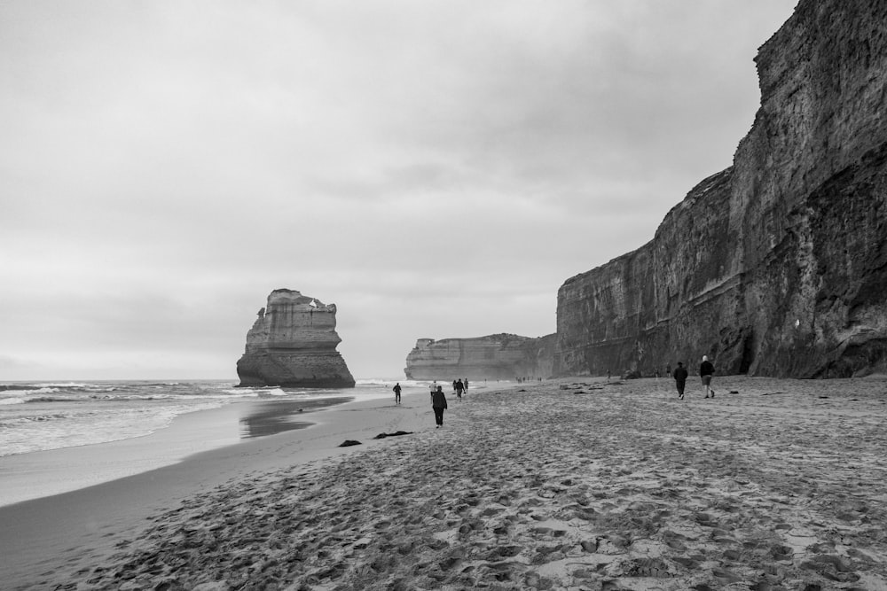 a group of people walking along a beach next to the ocean