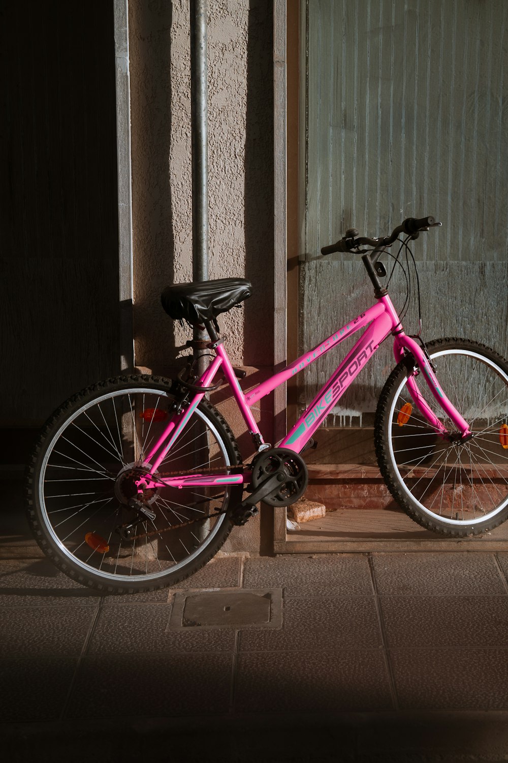 a pink bike parked next to a building