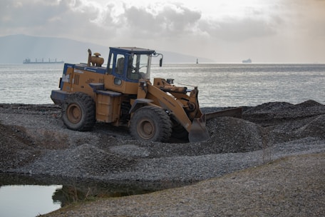a bulldozer is parked on a rocky beach