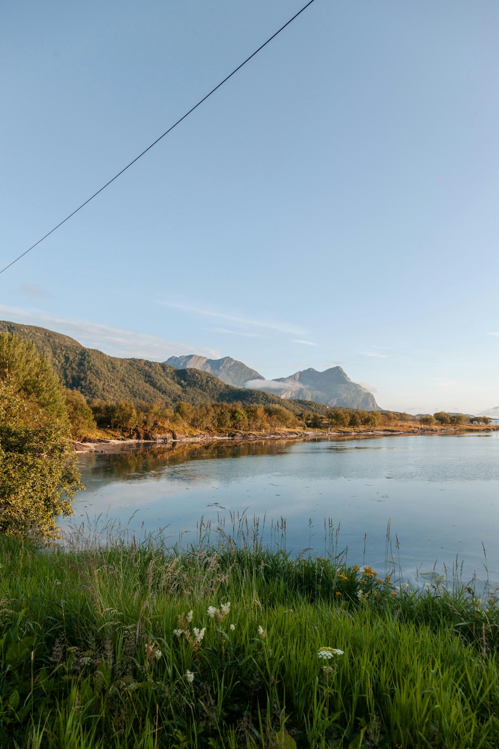 a body of water surrounded by mountains and grass