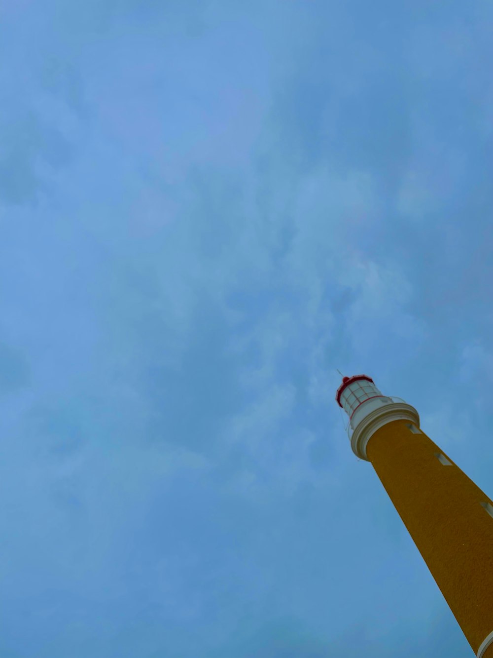 a tall light house sitting under a cloudy blue sky