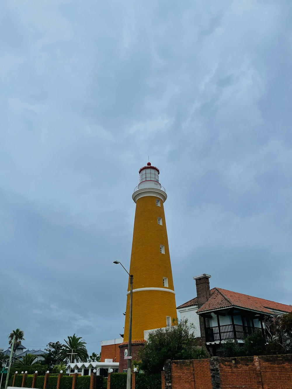 a yellow and white lighthouse on a cloudy day