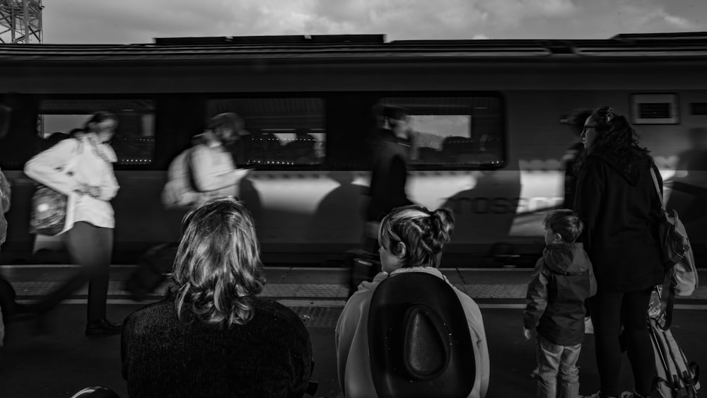 a black and white photo of people waiting for a train