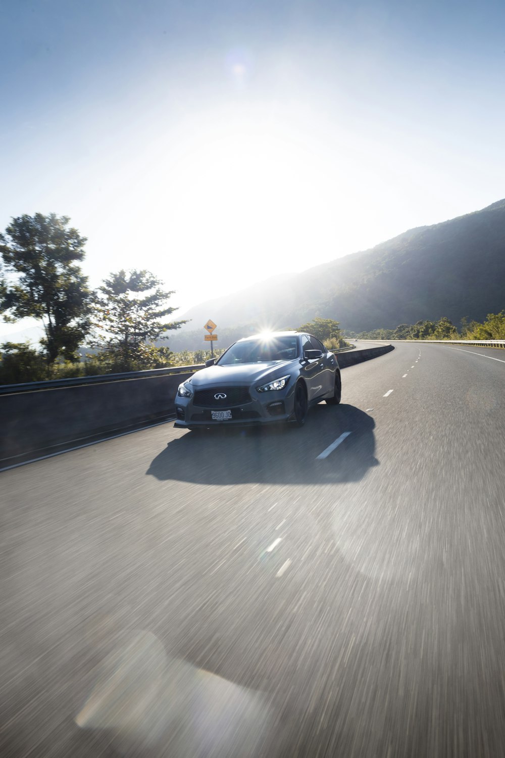 a silver sports car driving down a road