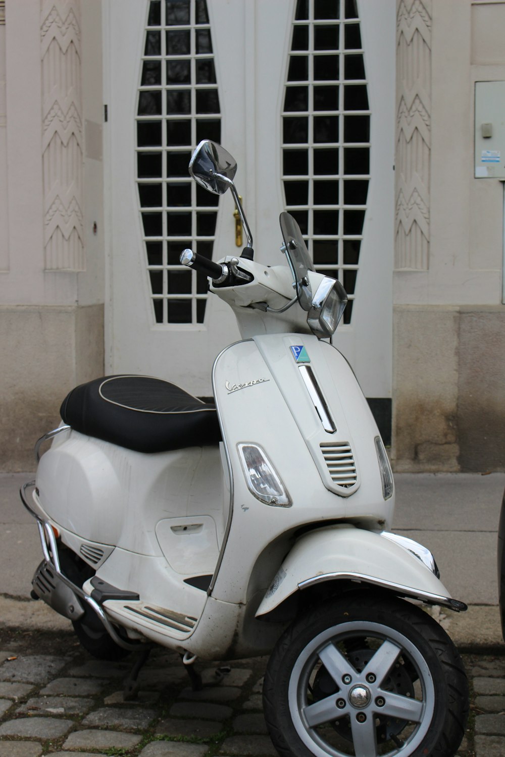 a white scooter parked in front of a building