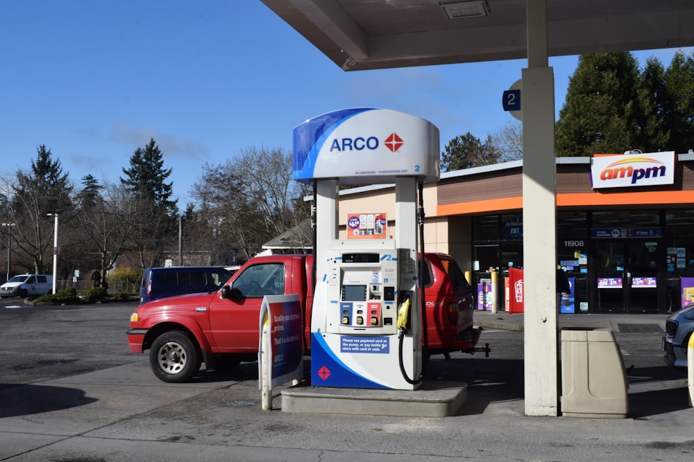 a red truck parked next to a gas station