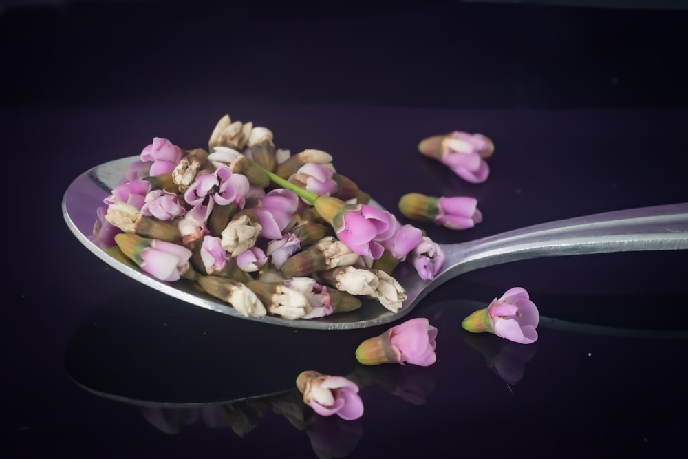 a spoon filled with flowers sitting on top of a table