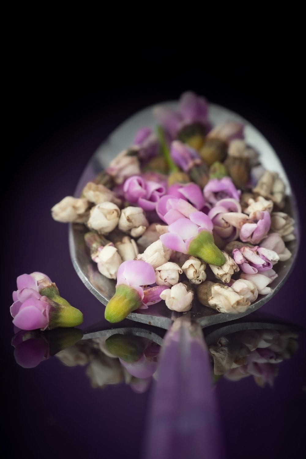 a spoon filled with flowers sitting on top of a table