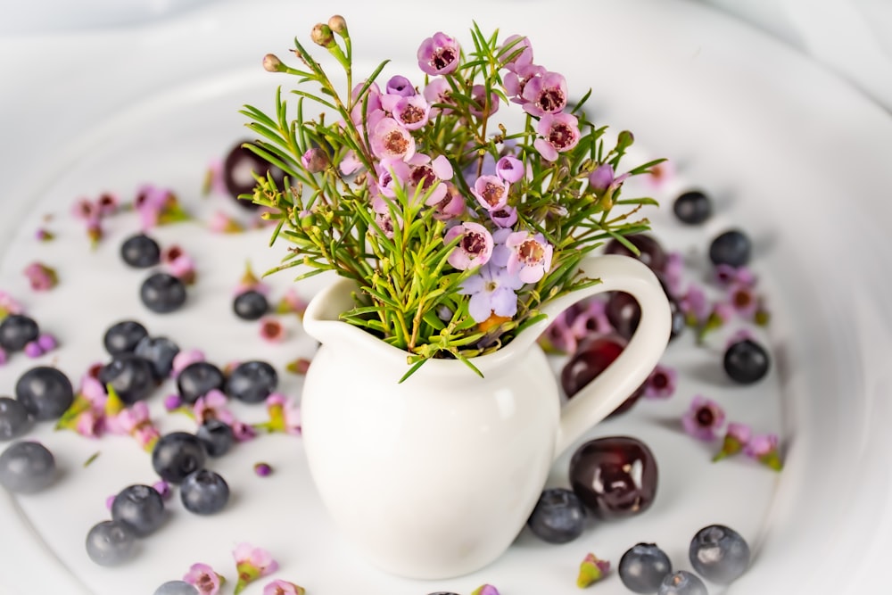 a white pitcher filled with blueberries and flowers