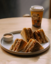 a white plate topped with sandwiches next to a cup of coffee