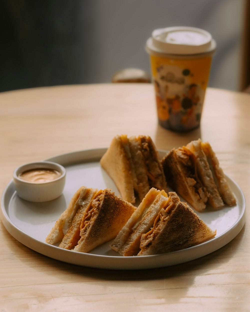 a white plate topped with sandwiches next to a cup of coffee