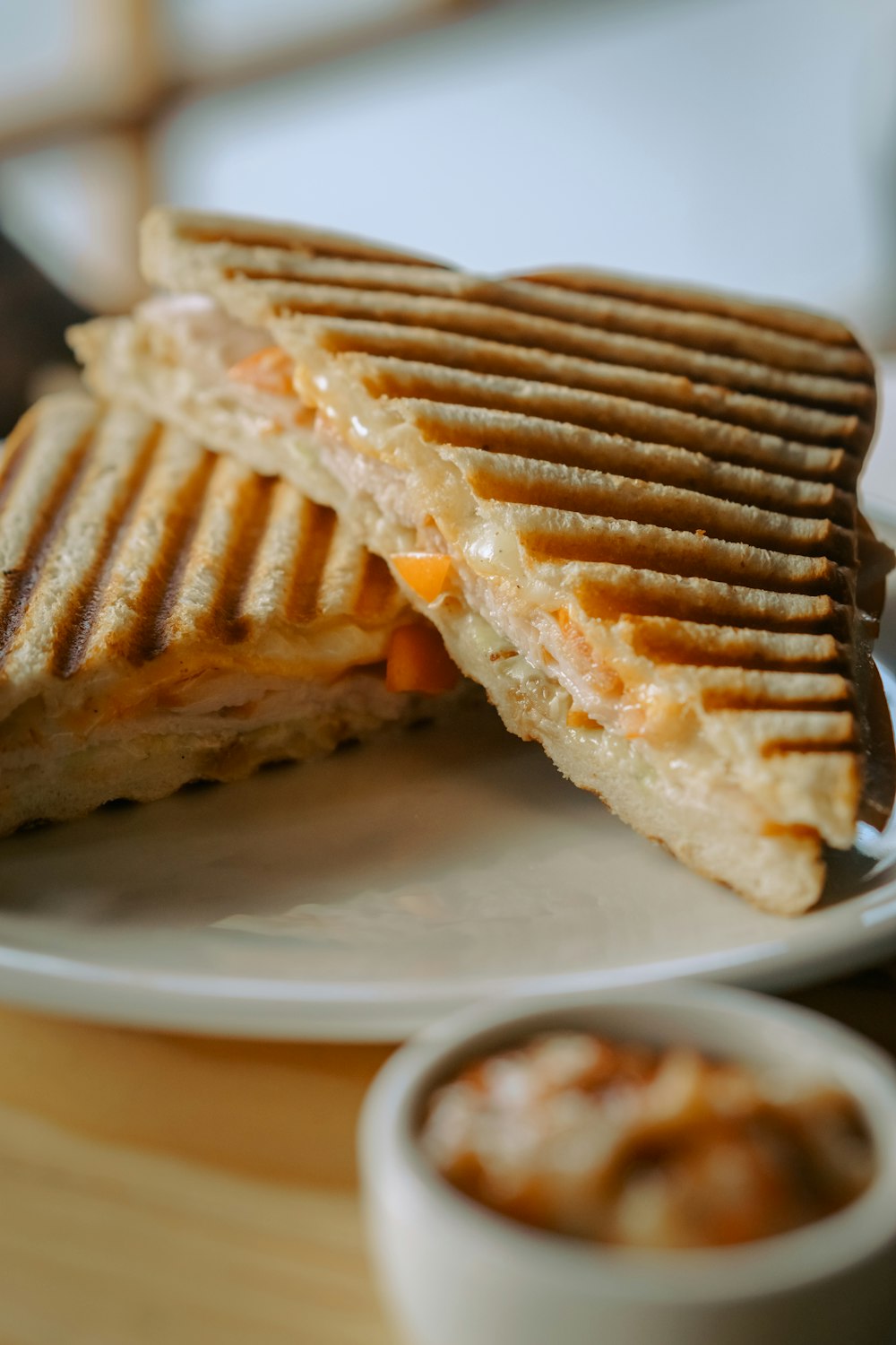 a grilled sandwich on a plate with a bowl of dipping sauce