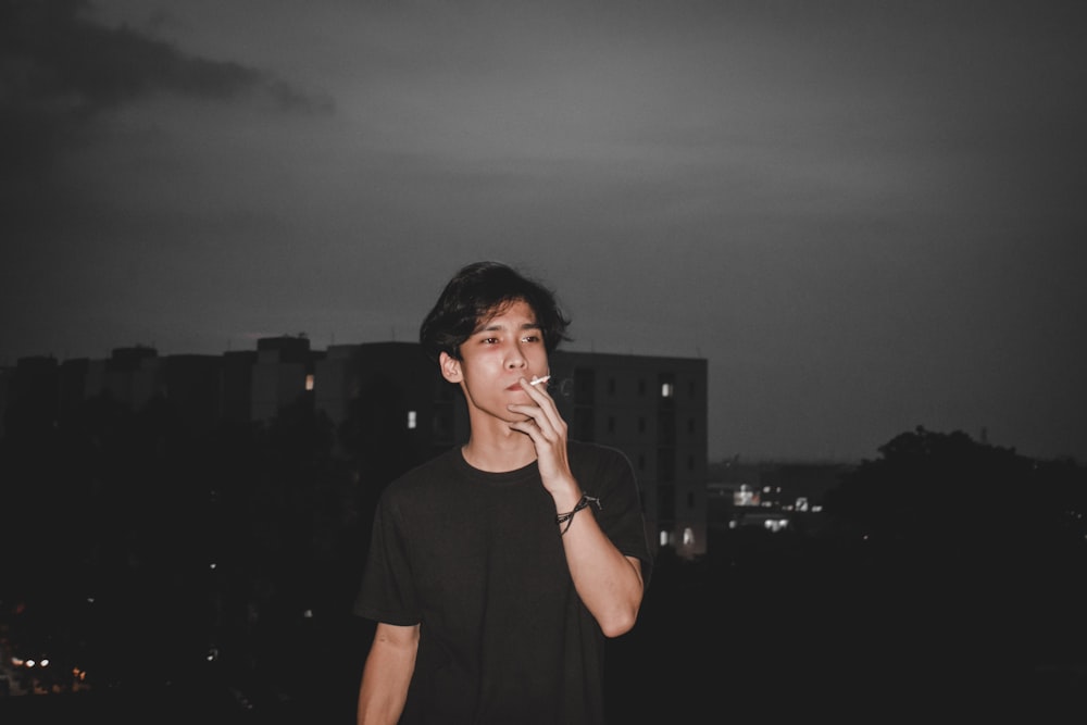 a young man smoking a cigarette in a city at night